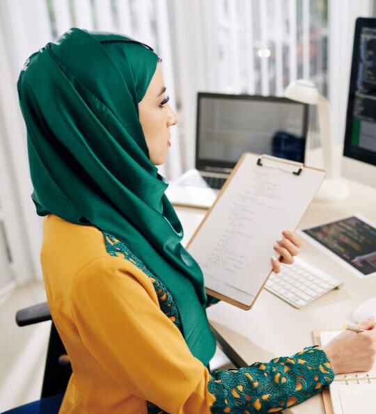 Serious pensive young Muslim software developer looking on programming code on computer screen and thinking how to make it better