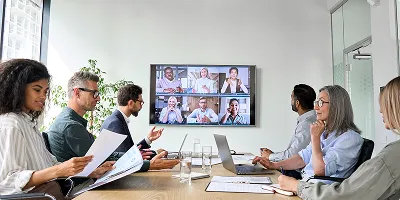 A group of diverse business professionals in a conference room having a hybrid meeting
