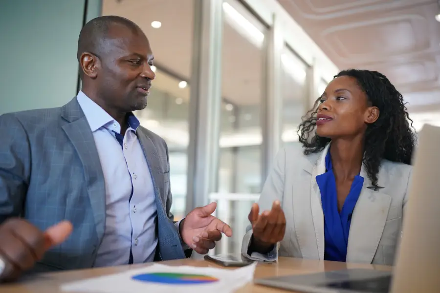 Africa US consultants collaboration reviewing business strategy charts and laptop at a modern conference table.