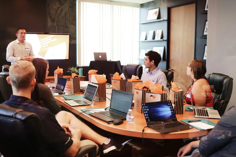 IT professionals attending a boardroom presentation with laptops and gift bags on a conference table.
