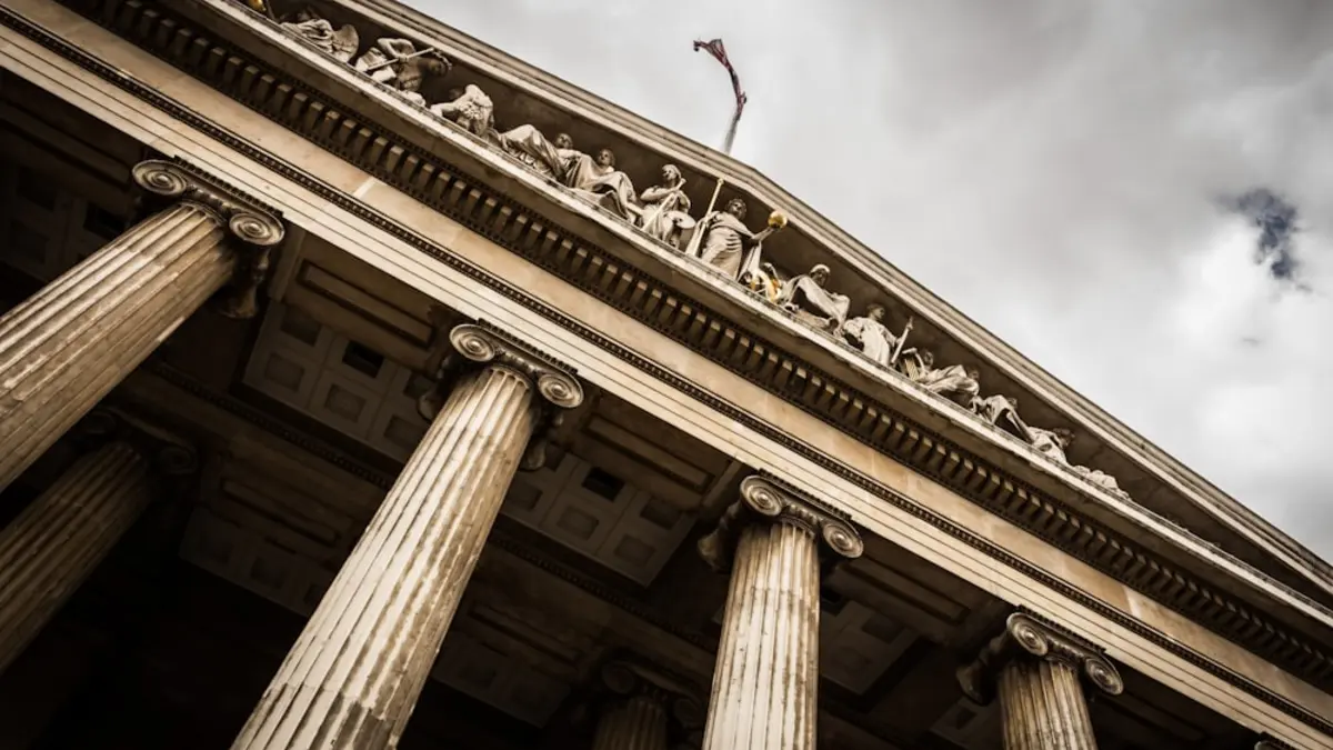 The stone columns and carved pediment of a classical civic building seen from below.