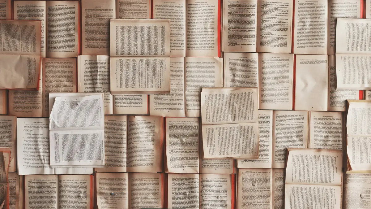 Dozens of open book pages laid edge to edge, filling the frame with printed text.