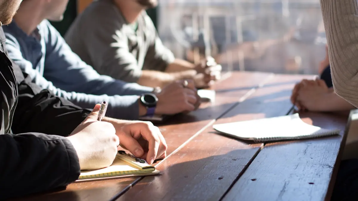 Four colleagues seated along a wooden table, writing notes during a working session.