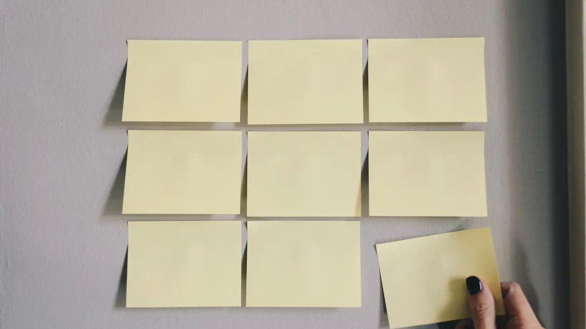 A hand placing a paper note into an ordered grid of notes on a wall.