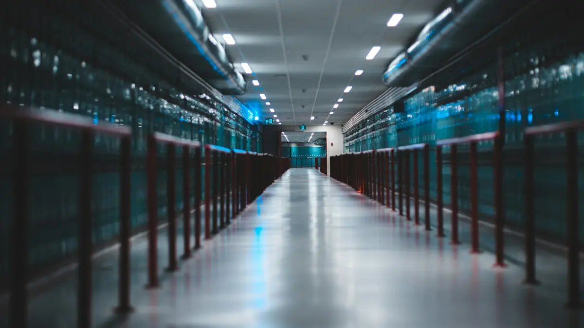A long aisle running between two rows of blue lit server cabinets in a data center.