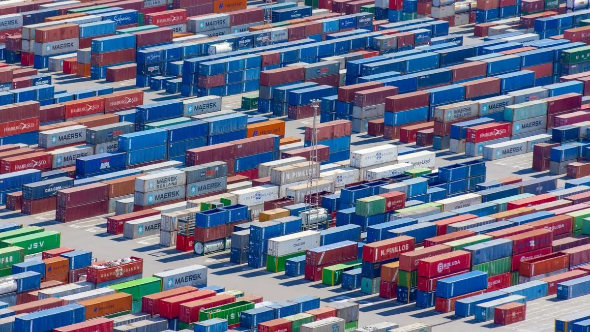 Rows of brightly coloured shipping containers stacked in a port, photographed from above.