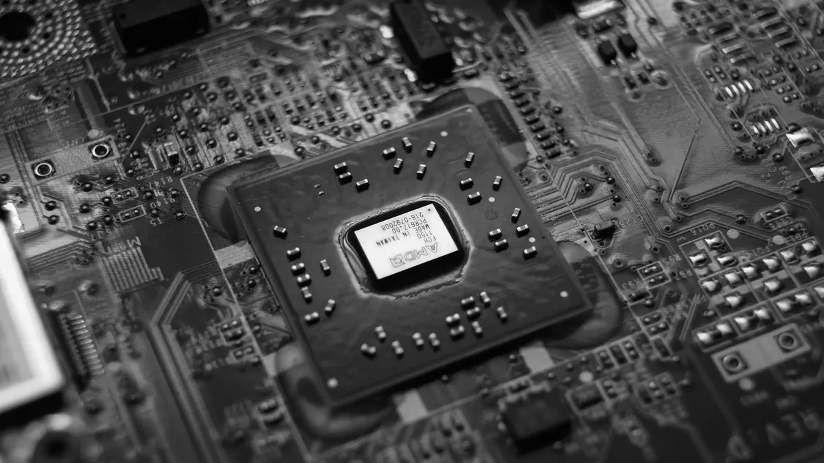 A black and white close view of a processor package mounted on a densely populated circuit board.