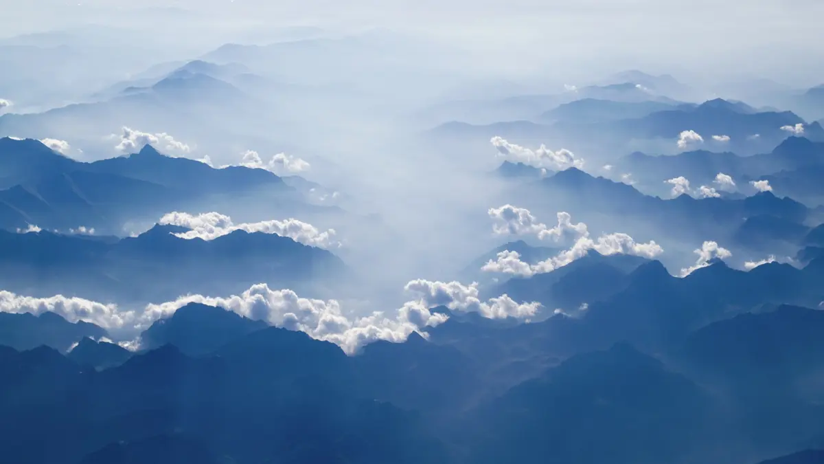 Blue mountain ridges receding into the distance through separated layers of cloud.