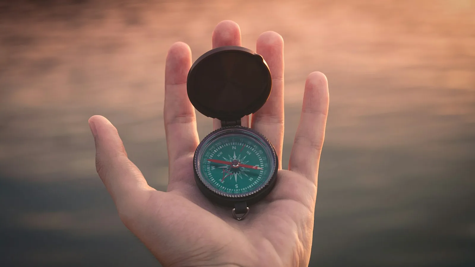 An open magnetic compass resting in an upturned palm.
