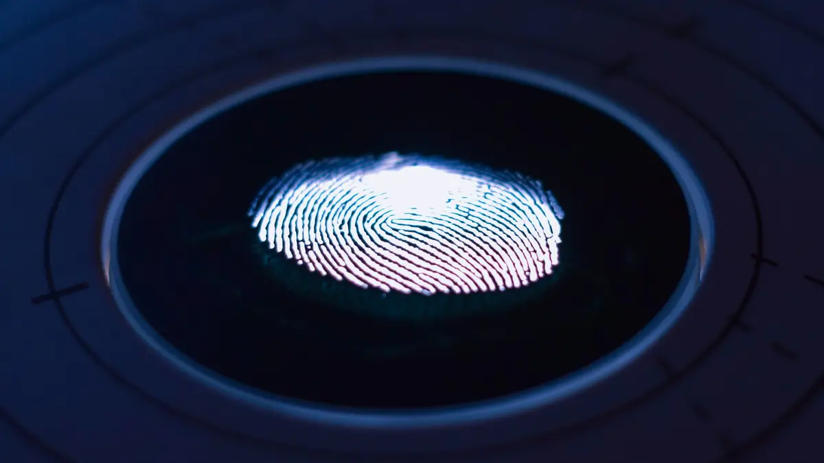 A glowing fingerprint on the surface of a dark circular biometric scanner.