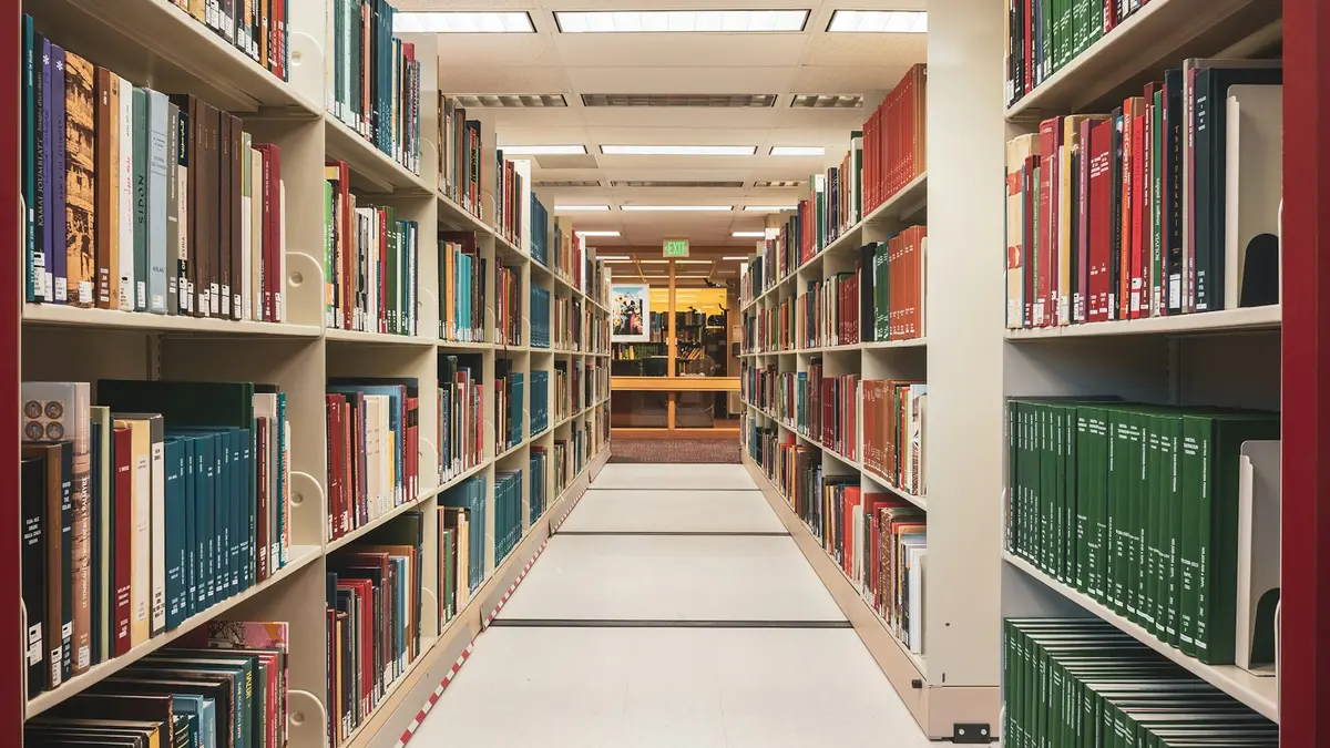 A corridor running between tall library shelves filled with bound volumes.