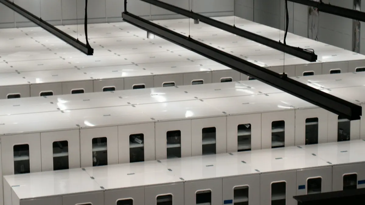Rows of white server cabinets seen from above in a brightly lit data center hall.