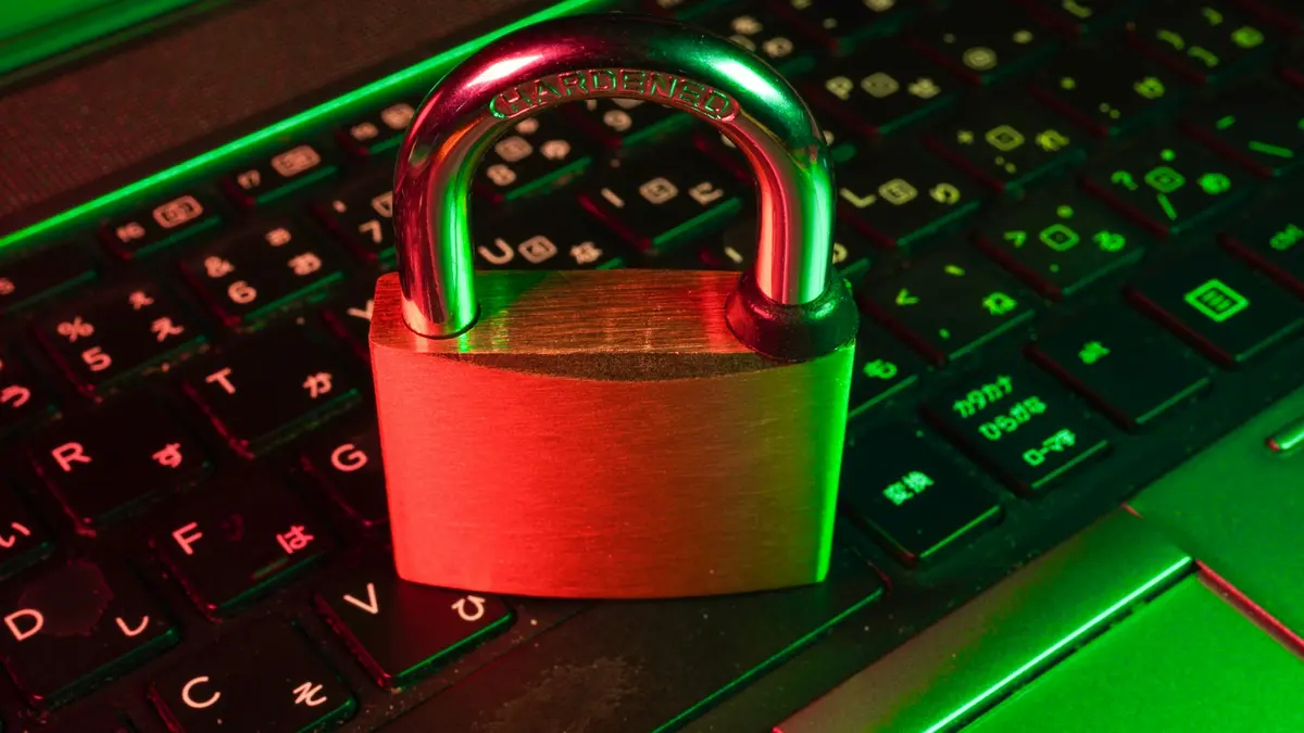 A metal padlock closed on top of an illuminated computer keyboard.