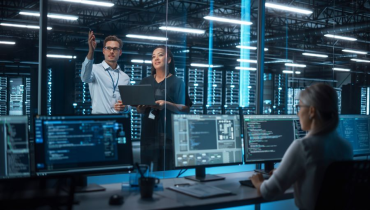 Female e-Business Entrepreneur and Male IT Specialist Discussing Something and Use Laptop in Big Data Center Server Room. 