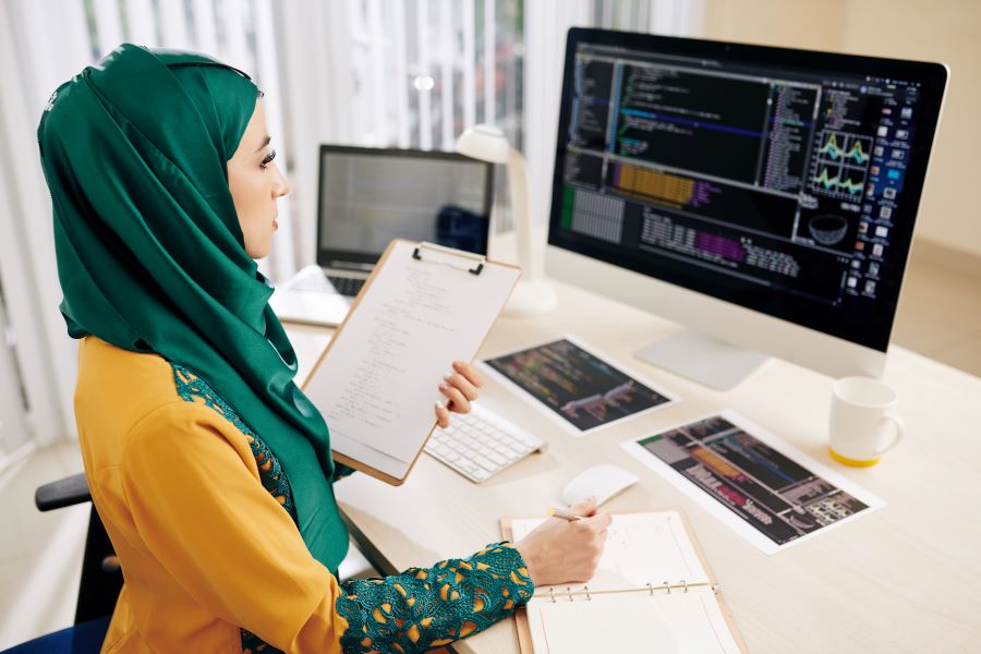 Serious pensive young Muslim software developer looking on programming code on computer screen and thinking how to make it better