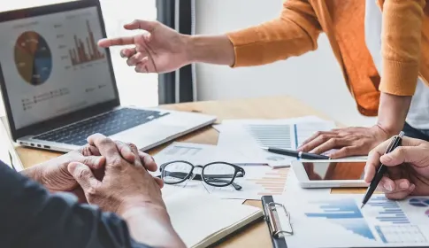 Three business professionals collaborating and analyzing data on a laptop
