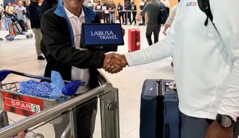 LT representative shakes hands with LABUSA Travel rep holding a tablet at Cape Town International Airport arrivals hall.