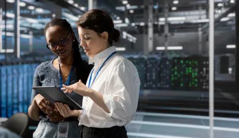 Africa government data center modernization with IT professionals reviewing operations on tablet in front of server racks.