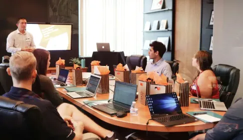 IT professionals attending a boardroom presentation with laptops and gift bags on a conference table.