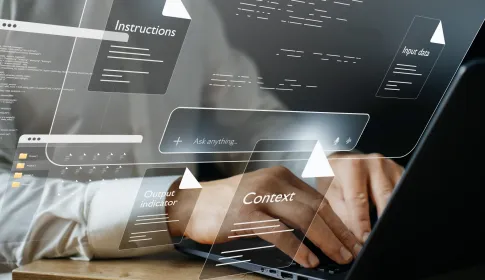 Professional typing on laptop surrounded by floating AI prompt interface elements: instructions; context; input data; and output indicators.