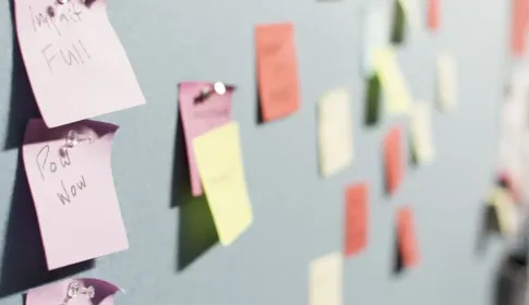 Handwritten sticky notes in several colours arranged across a pale wall.