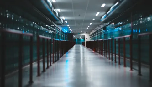 A long aisle running between two rows of blue lit server cabinets in a data center.