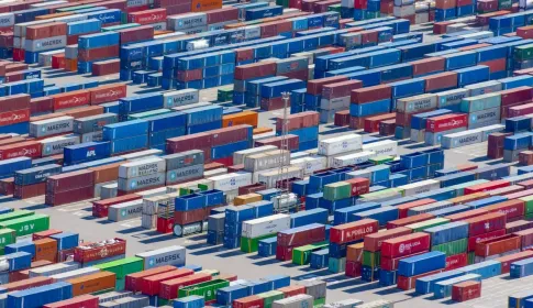 Rows of brightly coloured shipping containers stacked in a port, photographed from above.