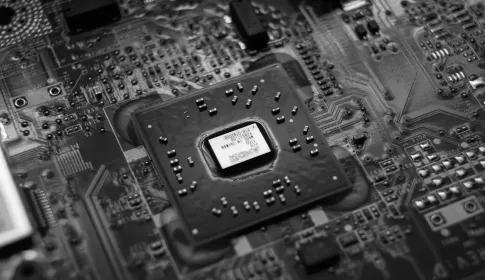 A black and white close view of a processor package mounted on a densely populated circuit board.