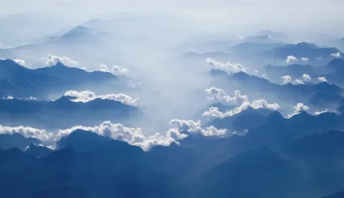 Blue mountain ridges receding into the distance through separated layers of cloud.