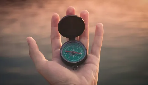 An open magnetic compass resting in an upturned palm.