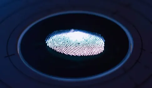 A glowing fingerprint on the surface of a dark circular biometric scanner.