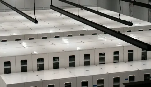 Rows of white server cabinets seen from above in a brightly lit data center hall.