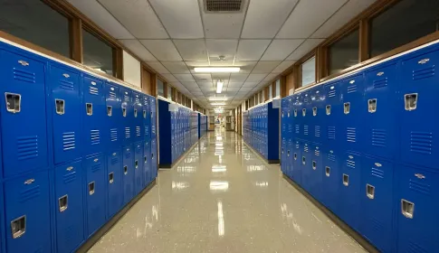 An empty school corridor lined on both sides with blue student lockers.