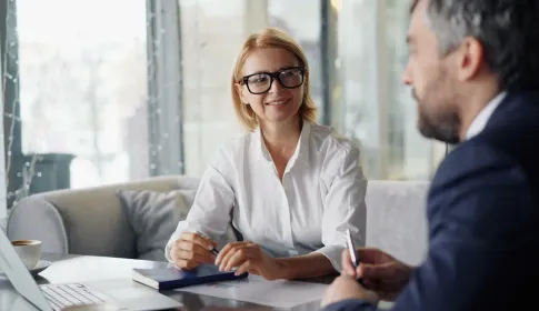 Two professionals reviewing a printed performance chart across a meeting table beside a laptop.