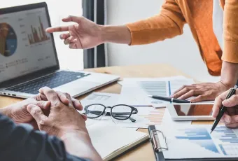 Three business professionals collaborating and analyzing data on a laptop