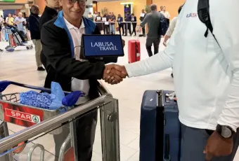 LT representative shakes hands with LABUSA Travel rep holding a tablet at Cape Town International Airport arrivals hall.