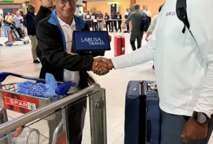 LT representative shakes hands with LABUSA Travel rep holding a tablet at Cape Town International Airport arrivals hall.