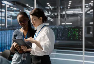 Africa government data center modernization with IT professionals reviewing operations on tablet in front of server racks.
