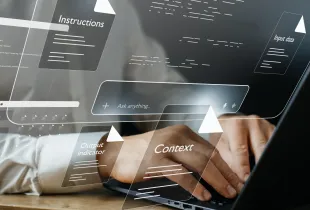 Professional typing on laptop surrounded by floating AI prompt interface elements: instructions; context; input data; and output indicators.