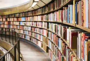 Curved shelves of a multi-level library filled with bound volumes.