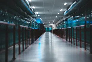 A long aisle running between two rows of blue lit server cabinets in a data center.