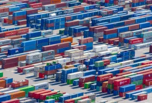 Rows of brightly coloured shipping containers stacked in a port, photographed from above.