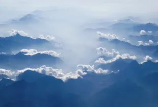 Blue mountain ridges receding into the distance through separated layers of cloud.