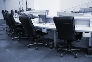 Empty local government council chamber with a curved dais, leather chairs, monitors and microphones.