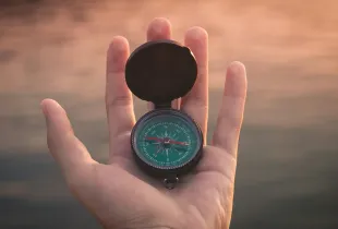 An open magnetic compass resting in an upturned palm.
