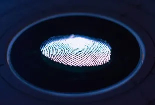 A glowing fingerprint on the surface of a dark circular biometric scanner.