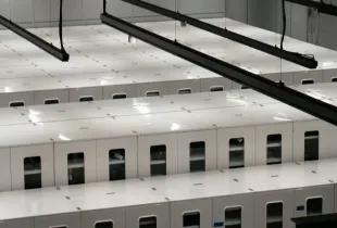 Rows of white server cabinets seen from above in a brightly lit data center hall.