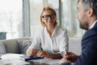 Two professionals reviewing a printed performance chart across a meeting table beside a laptop.