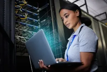 A woman working on a laptop in a server room