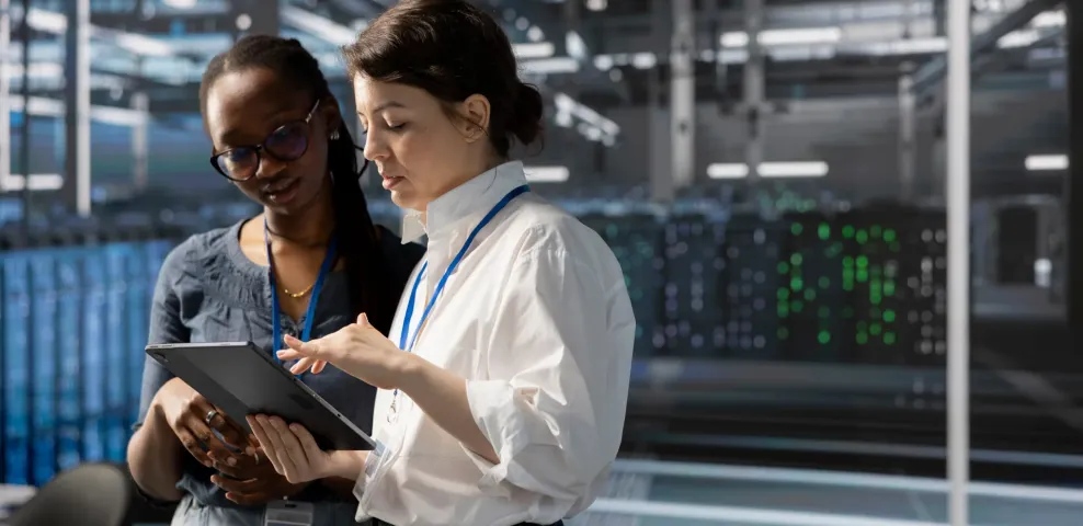 Africa government data center modernization with IT professionals reviewing operations on tablet in front of server racks.